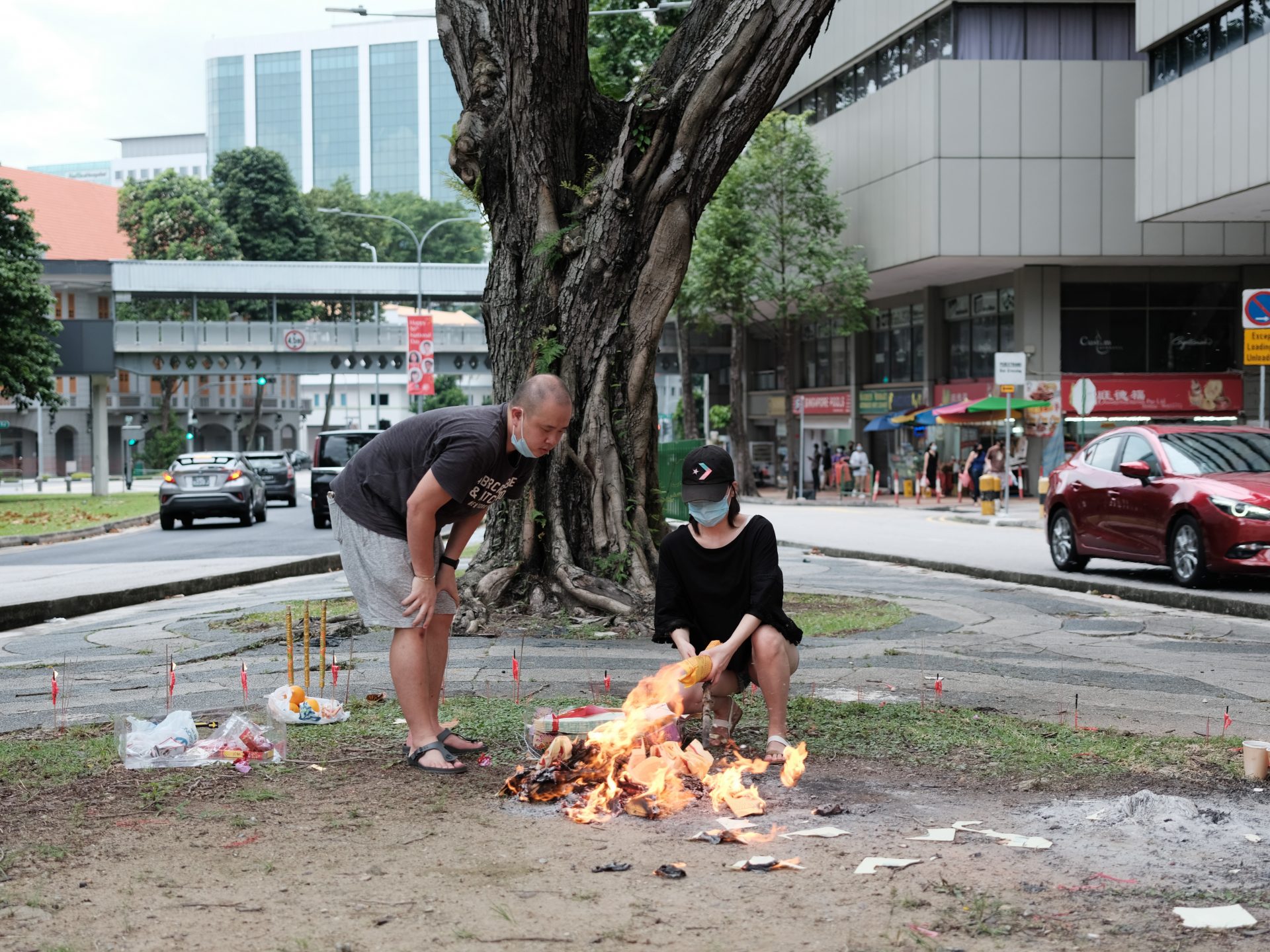 man in black t-shirt and gray shorts holding burning wood during daytime